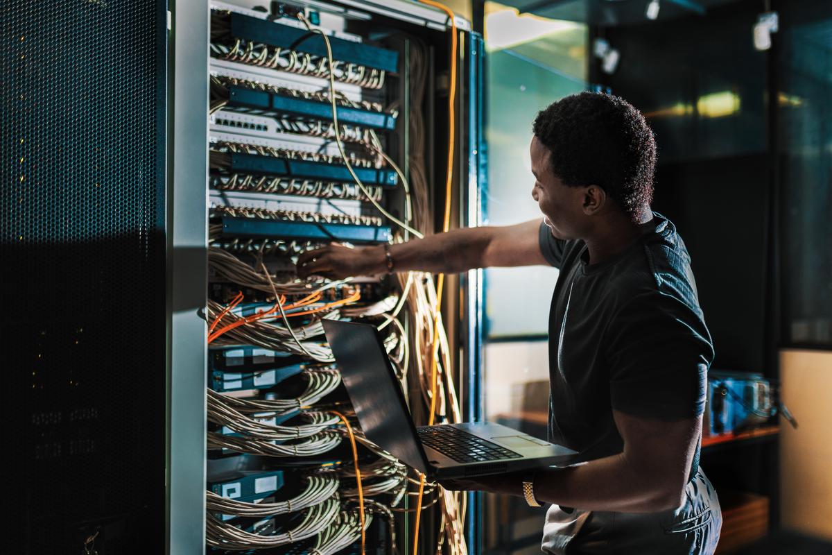 System administration, man is working in data center with laptop